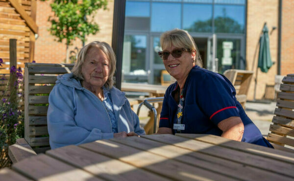 a carer and resident sitting in the garden in the sun