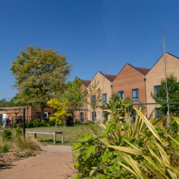 Outside Grounds showing clear blue skies in beautiful open plan garden. With one of our residents getting their laps in around the garden