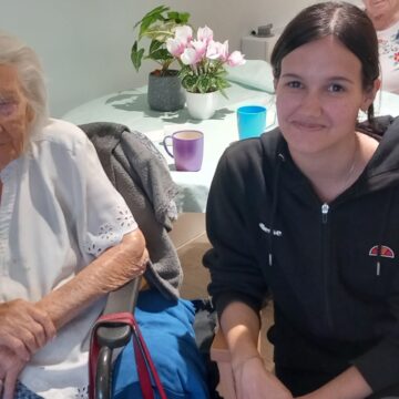 Patricia our Work Experience Student sitting smiling with one of our residents