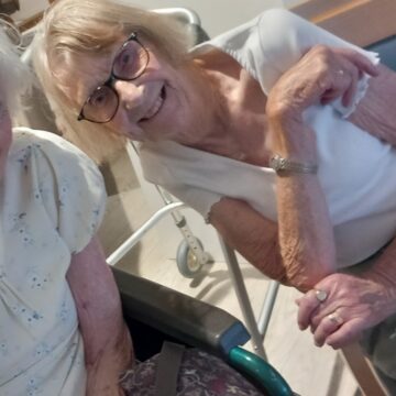 Photo of Residents in their chairs listening to Peter George singing and playing his guitar