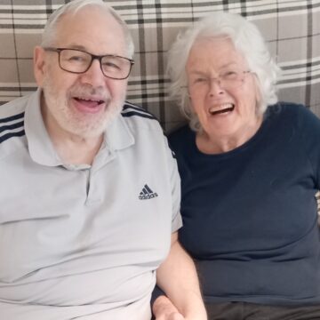 Photo of Residents in their chairs listening to Peter George singing and playing his guitar
