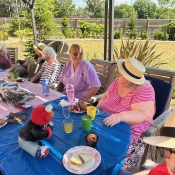 Residents sitting under the shaded area enjoying the picnic