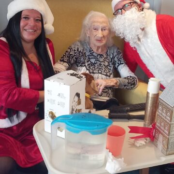 Mrs and Mrs Claus opening presents with a resident