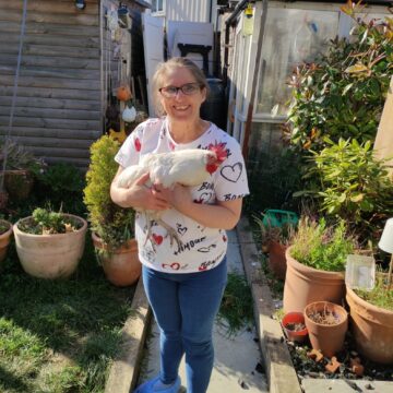 Service User holding up a chicken in the garden