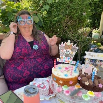 Service Users Birthday celebrations with cake and party sun glasses sitting outside