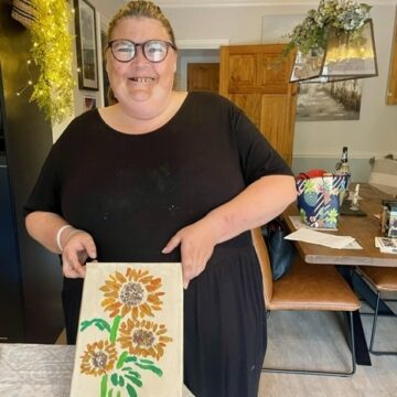Service User holding up a picture of sunflowers