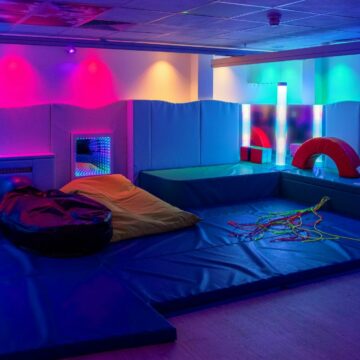 Sensory room with red yellow and green soft lighting and soft furnishings