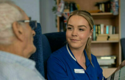 Care Staff reading newspaper with resident